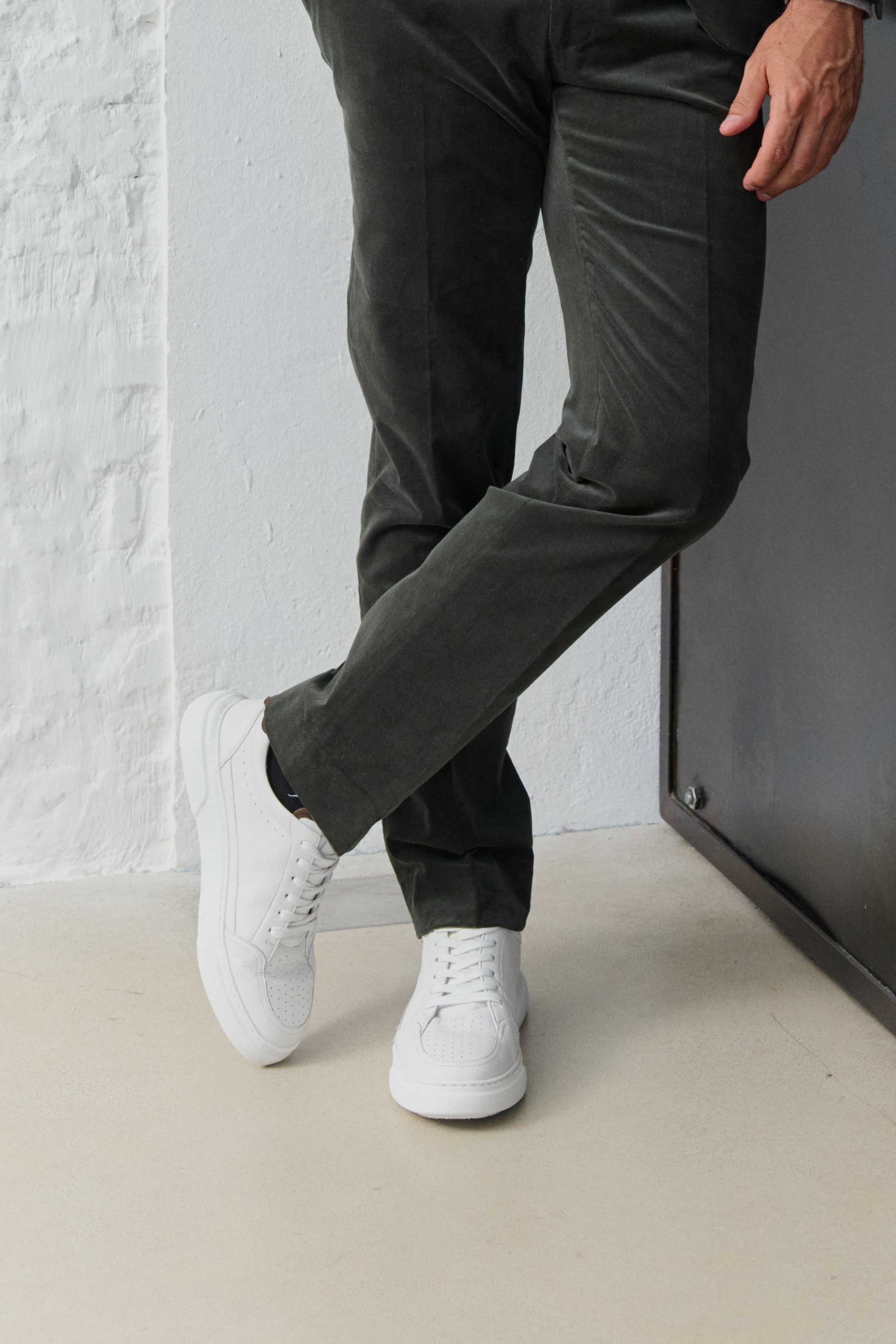 Mann trägt grüne Hose und weiße Sneaker.