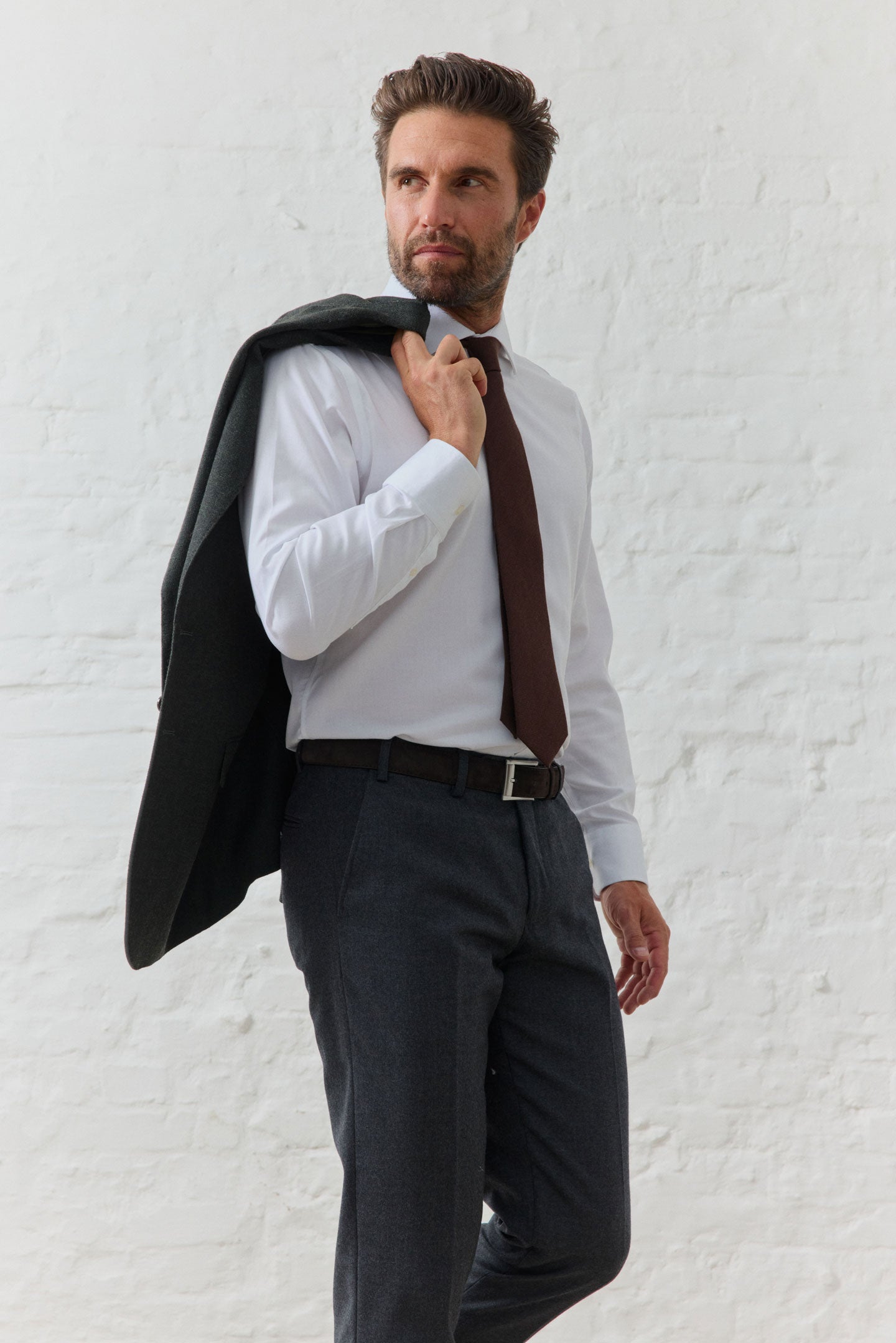 Mann in Anzug mit Krawatte und Jacke über Schulter.