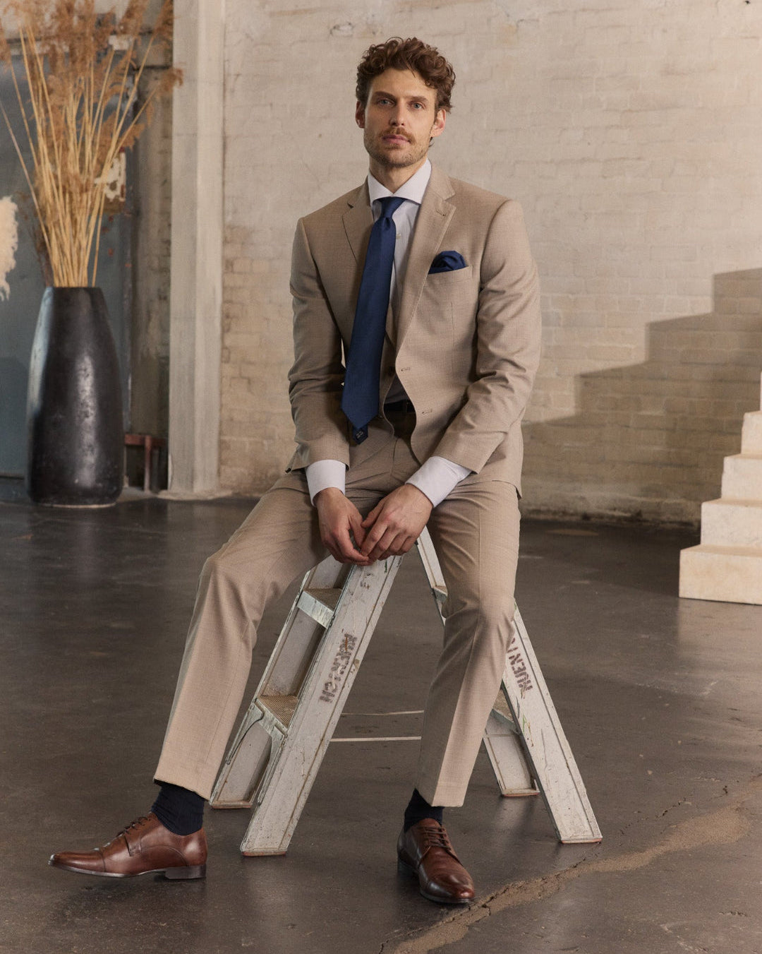 Mann in Anzug auf Leiter sitzend