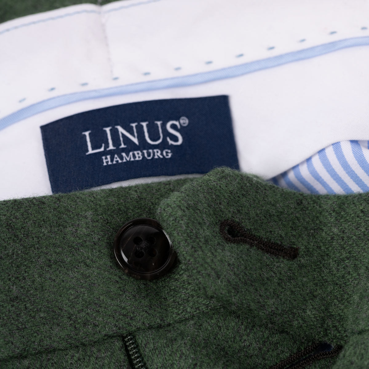 Grüner Mantel mit LINUS-Etikett.