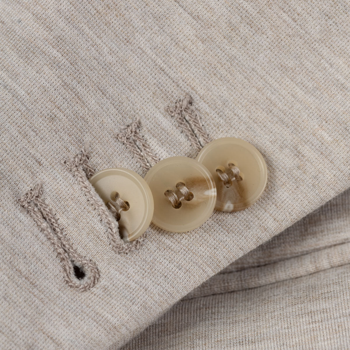 Beige Anzugknöpfe und Knopflöcher.