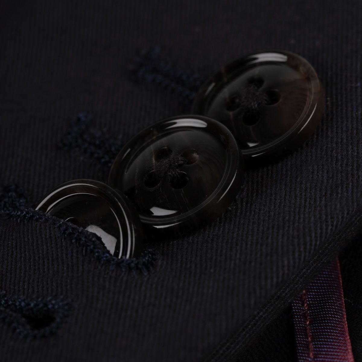 Dunkle Knöpfe auf Anzugstoff.