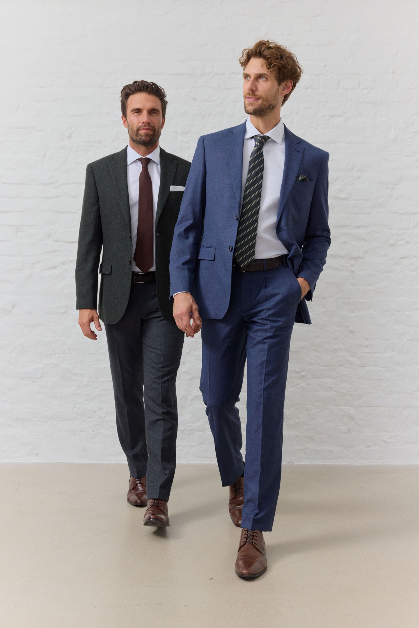 Zwei Männer in Anzügen, einer blau, einer grau.