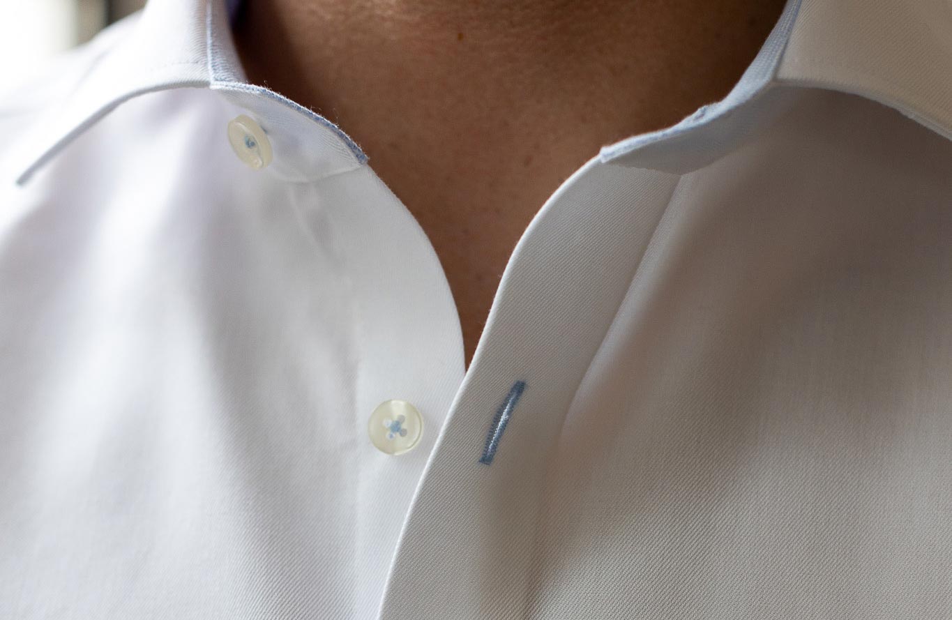 Nahaufnahme eines weißen Hemdkragens mit blauen Details.