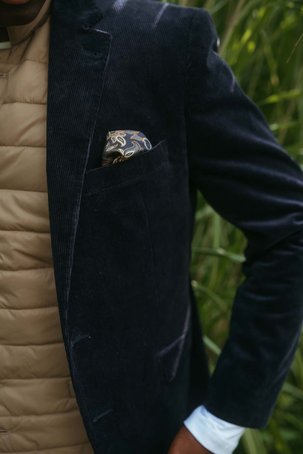 Mann trägt Cordjacke mit Einstecktuch und Steppweste.